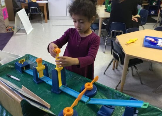 Child playing with a toy track on a green table