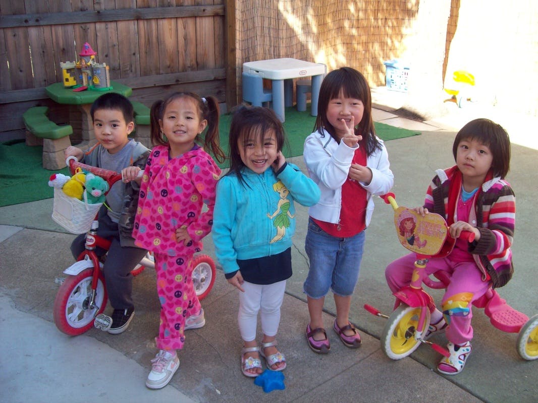 Five children with tricycles in a play area