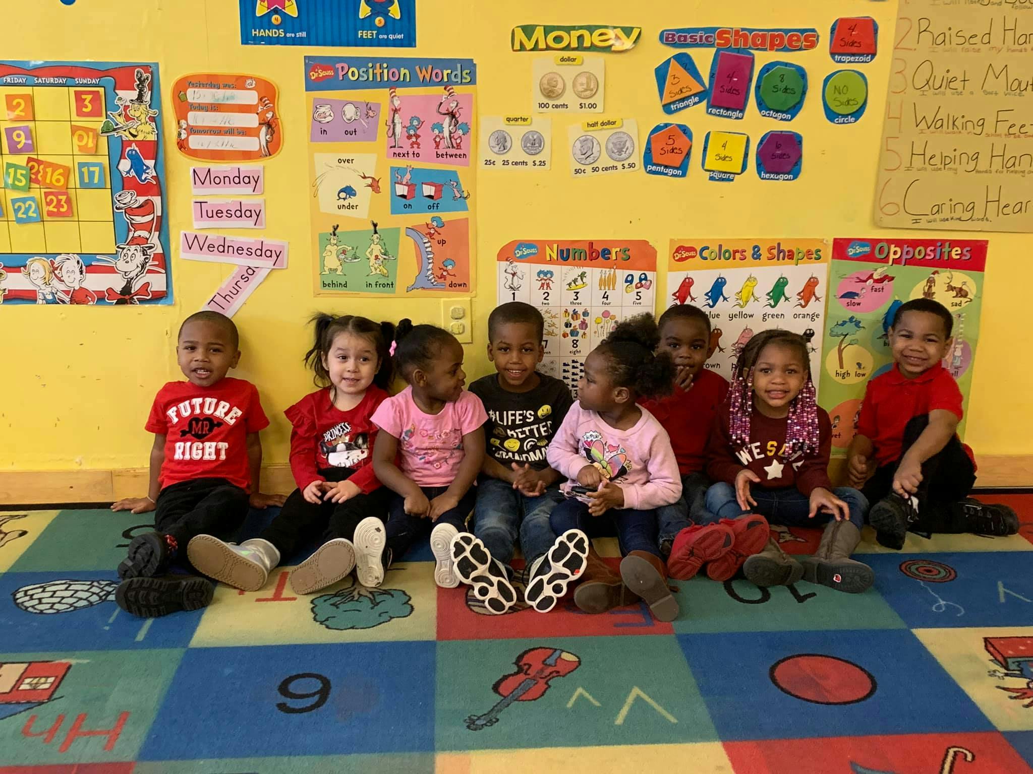 Group of children sitting on a colorful rug in a classroom