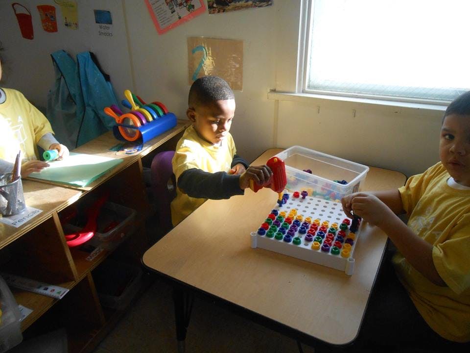 Child playing with colorful pegs on a board at a table
