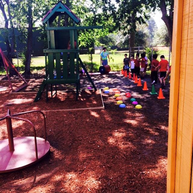 Children on a playground with play structure and cones
