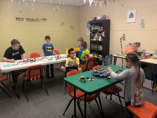 Children playing with building blocks at tables in a room