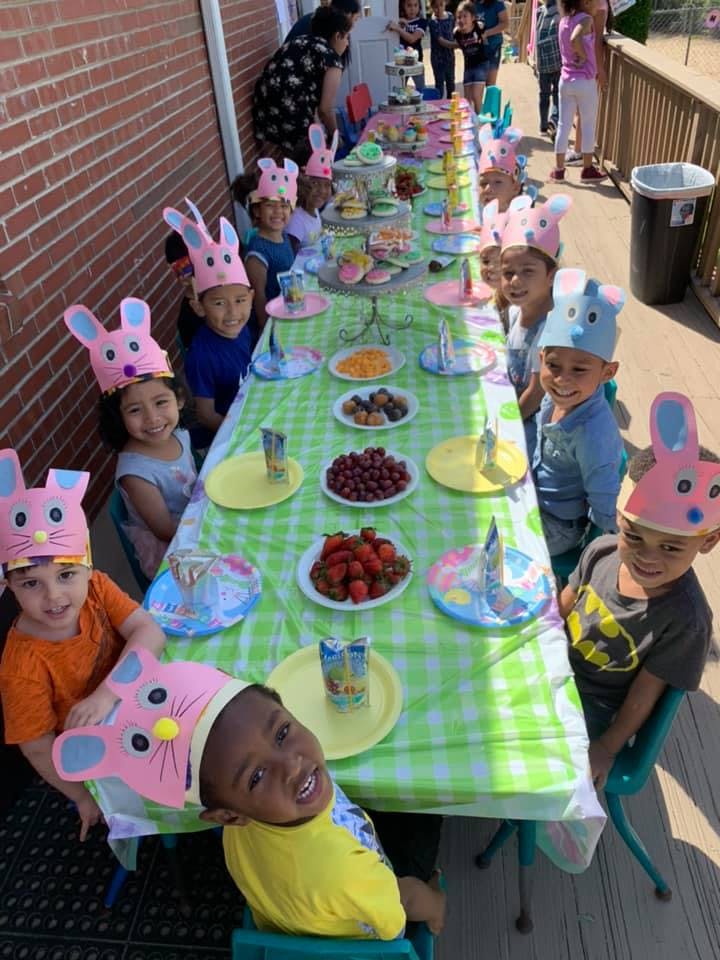 Children wearing bunny ear headbands at a table with fruit and snacks