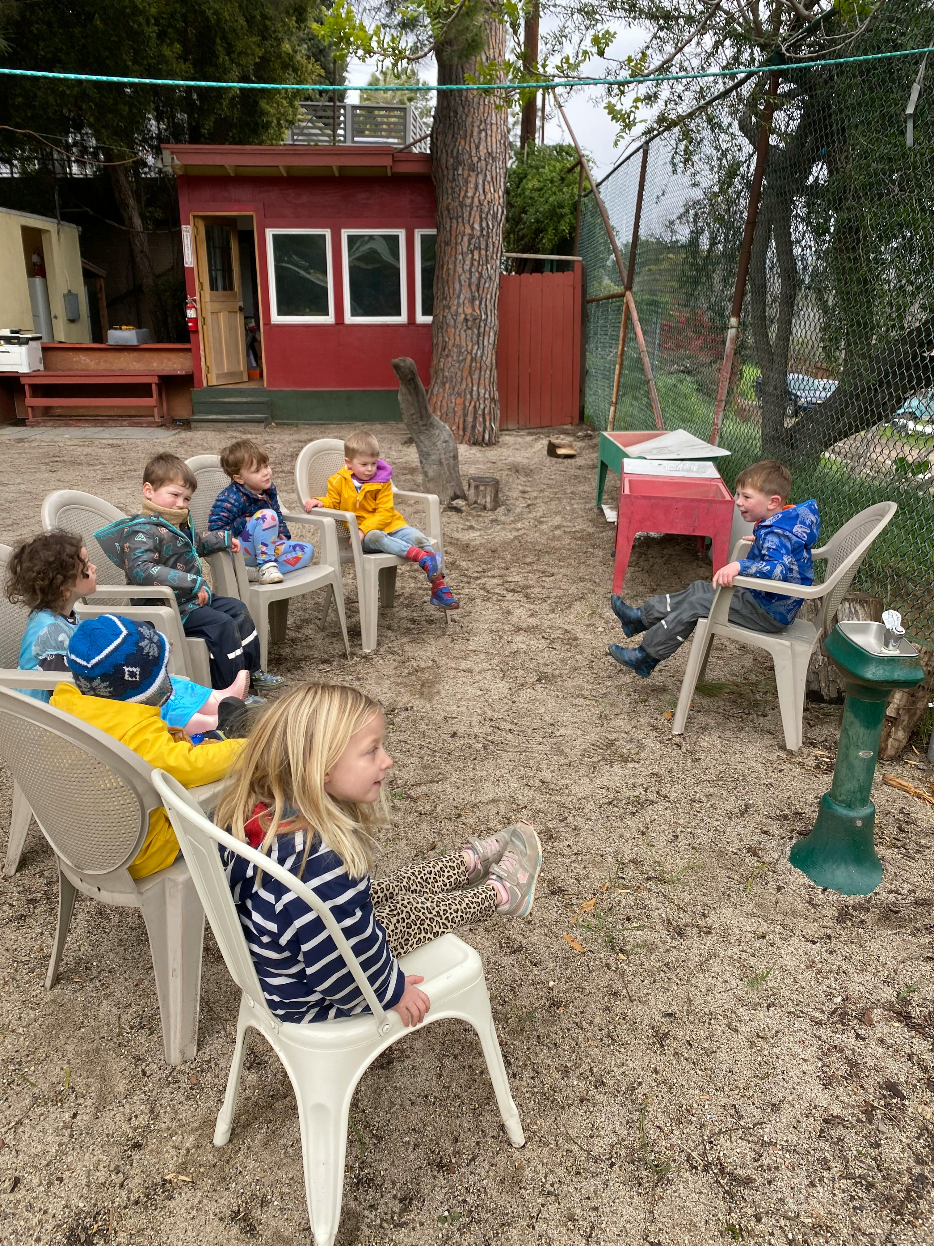 Group of children sitting on chairs outdoors