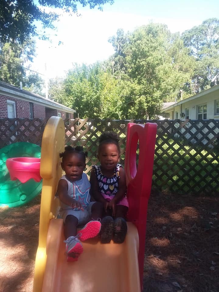 Two children sitting on a small slide outdoors