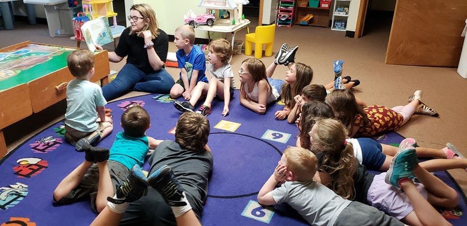 Person reading a book to a group of children
