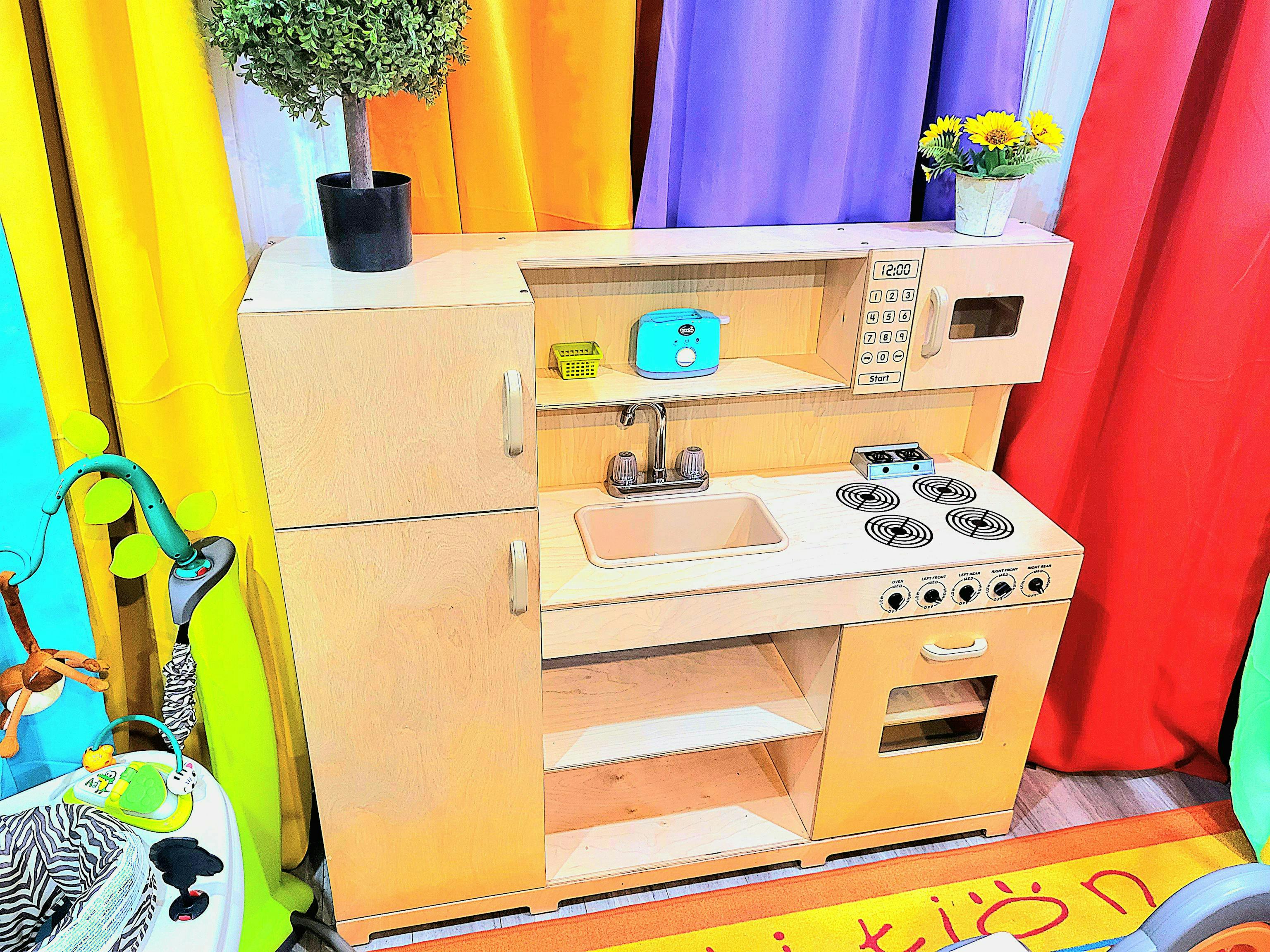 Wooden play kitchen with a refrigerator, sink, stove, and microwave