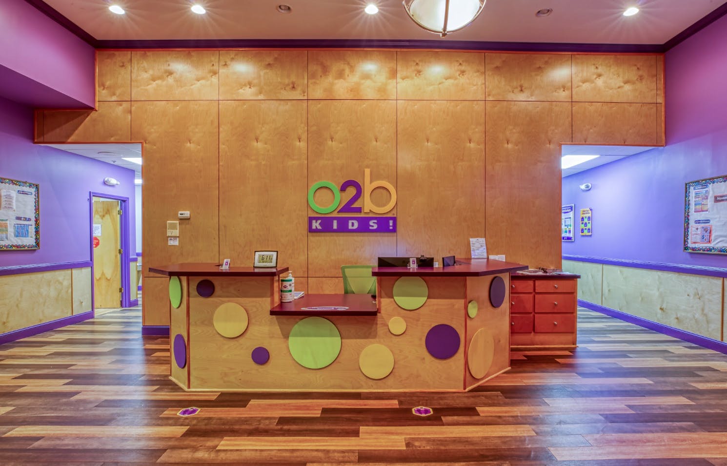 Reception desk with colorful circles, two doorways, and the O2b Kids! logo