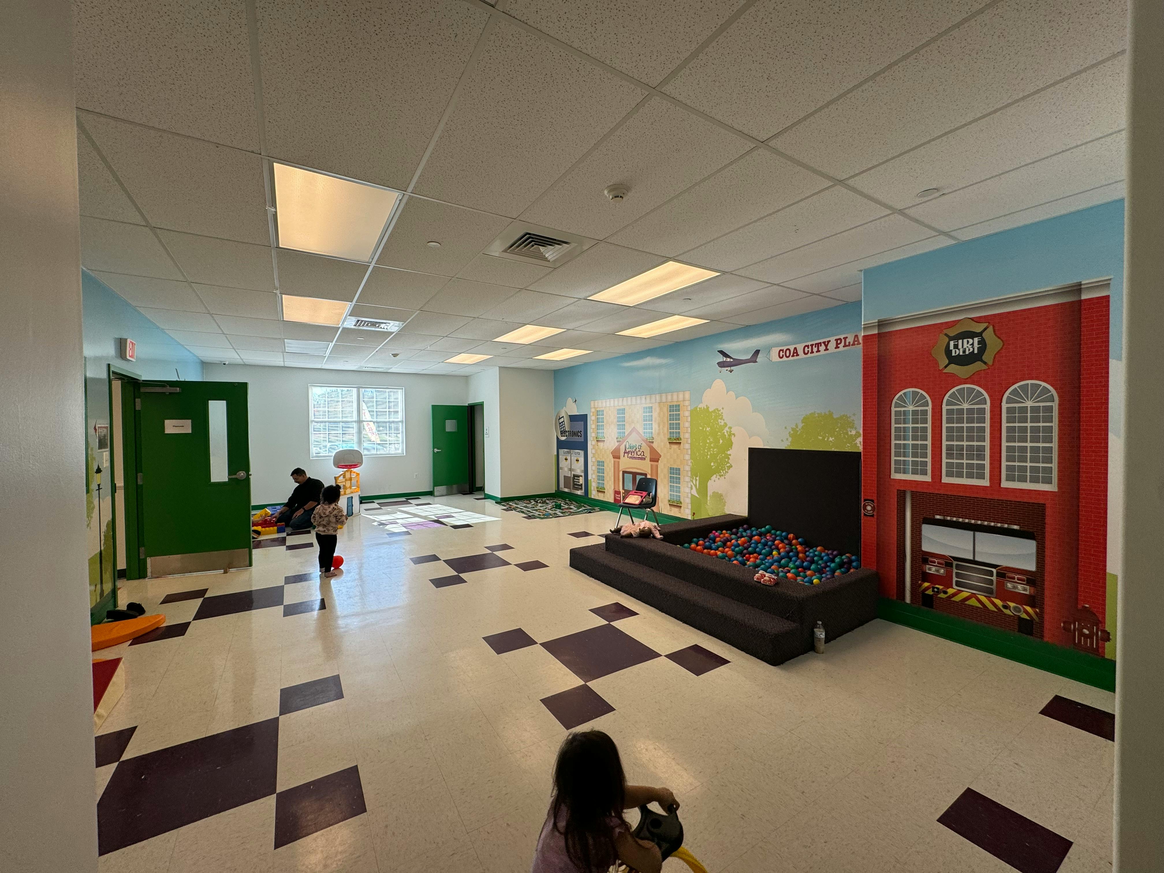 Children playing in a room with a ball pit and wall murals