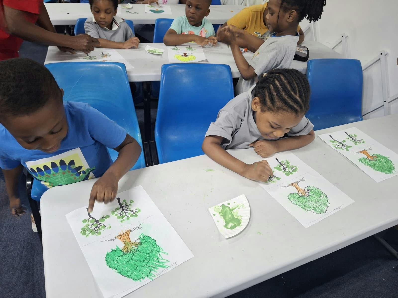 Children sitting at tables drawing trees in a classroom