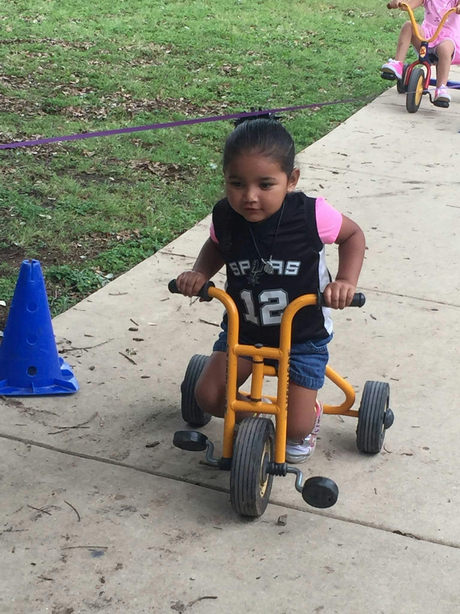 Child riding a tricycle on a sidewalk