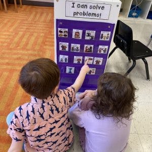 Two children looking at a chart with the text "I can solve problems!"