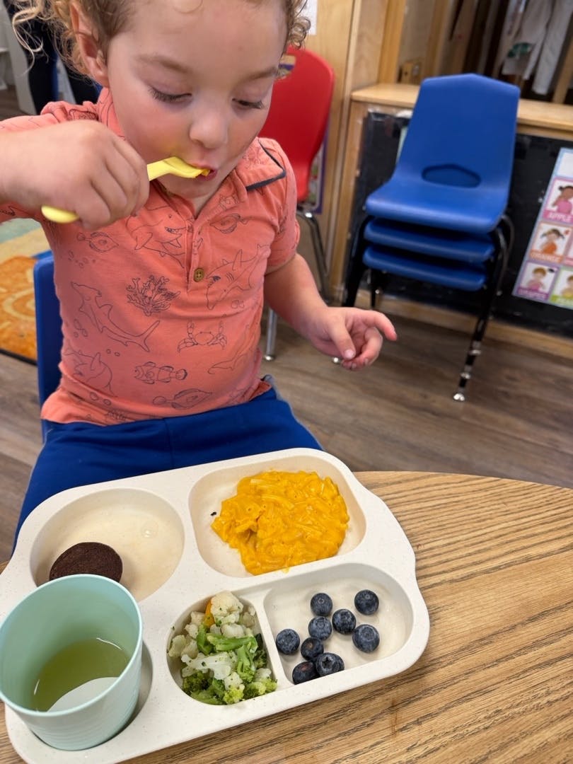 Child eating from a divided plate with a spoon