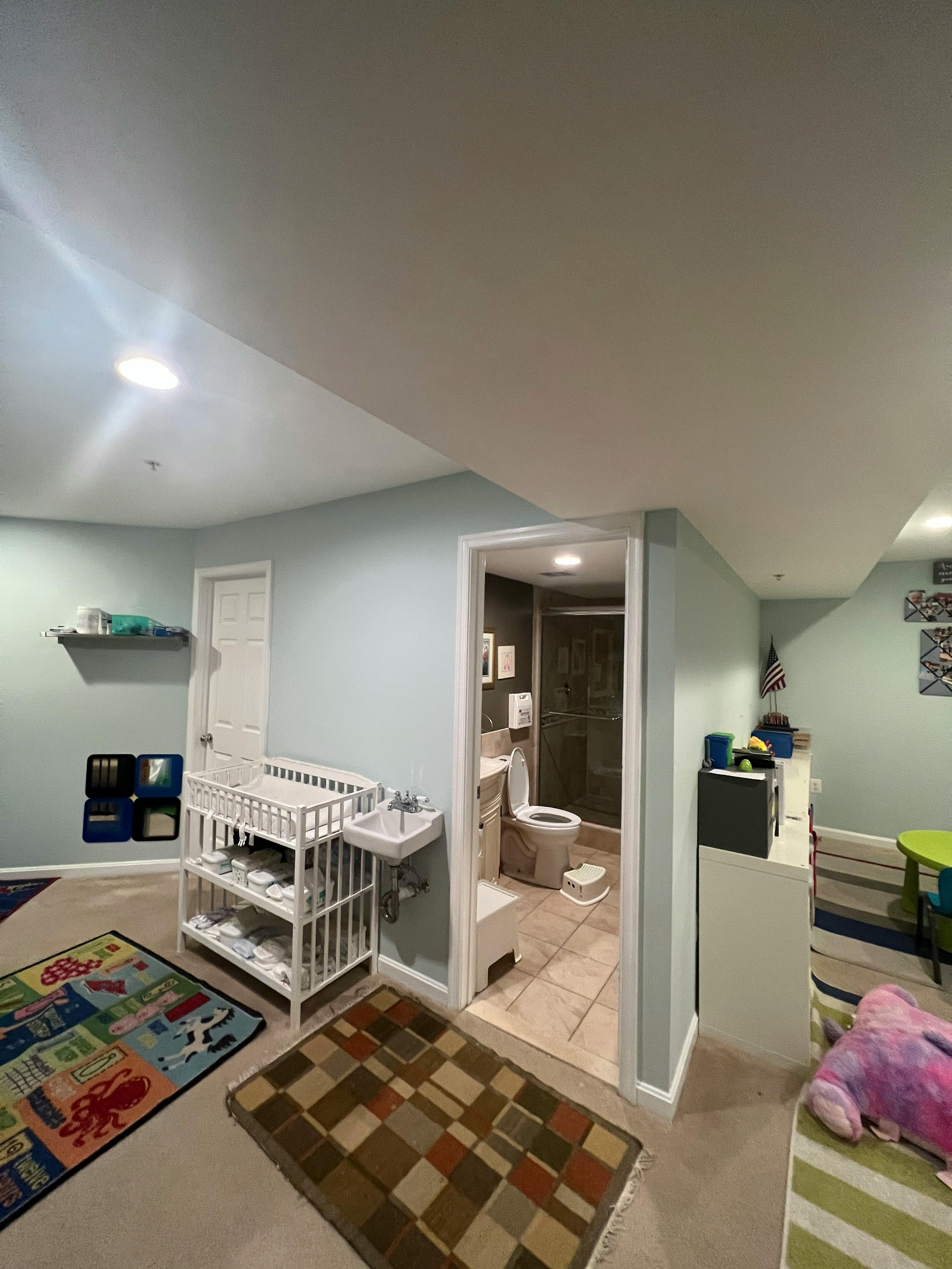 Room with a changing table, small sink, and an open doorway to a bathroom