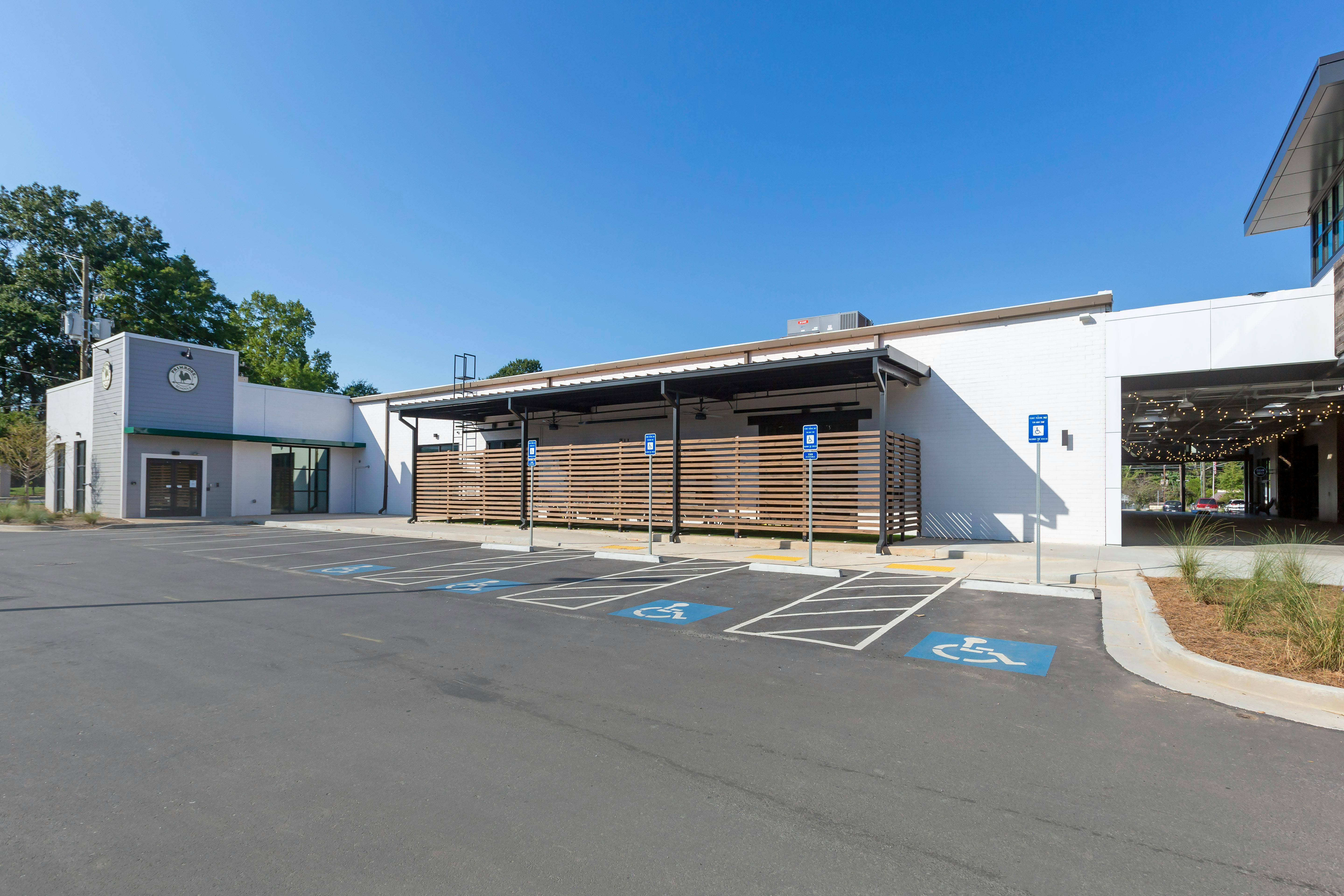 Parking lot with accessibility spaces in front of a white building with an outdoor patio