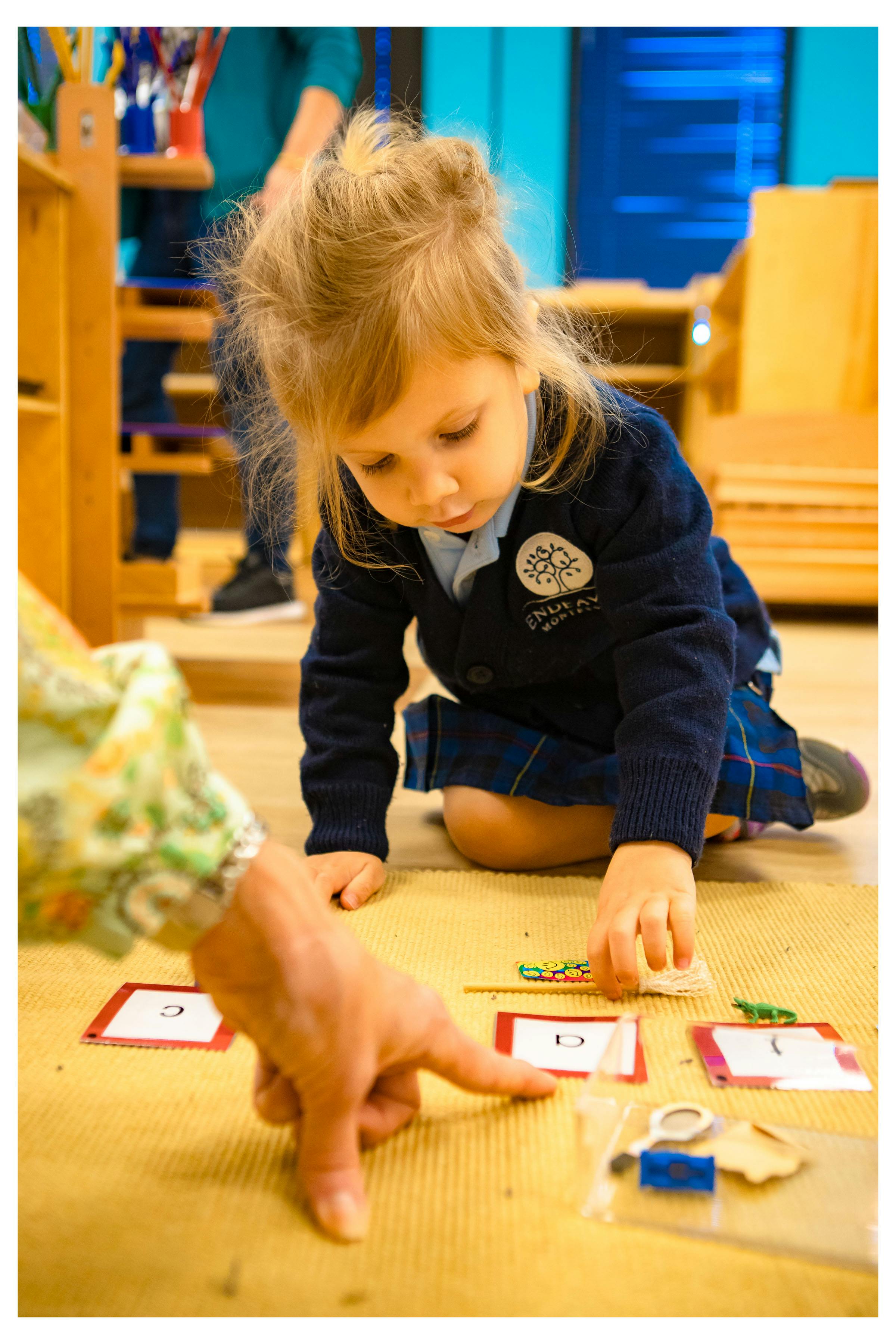 Child and adult on floor with learning cards