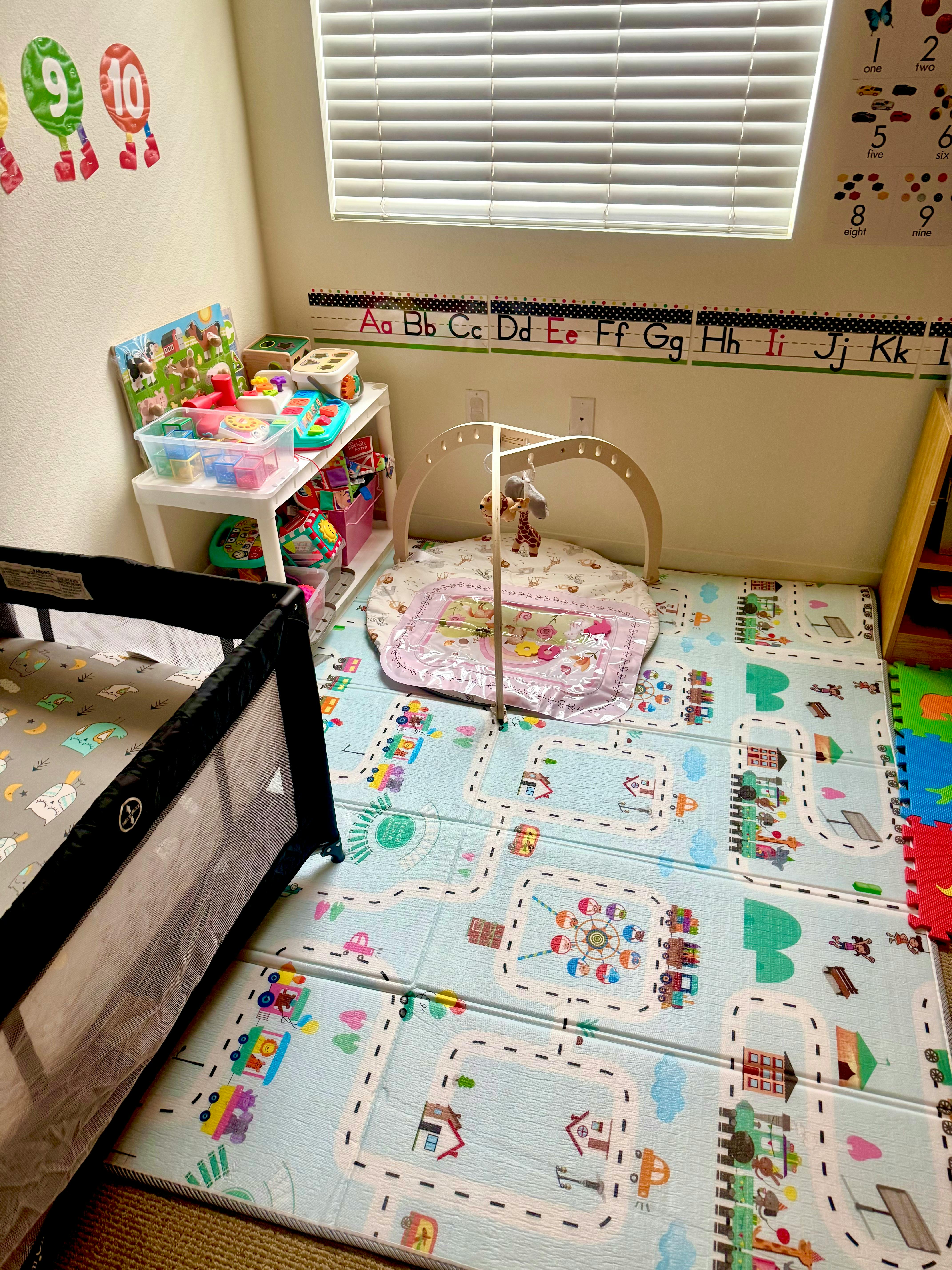 Playroom with a crib, playmat, and toy shelf