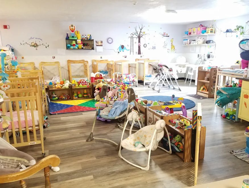 Daycare room with cribs, playmats, and baby swings