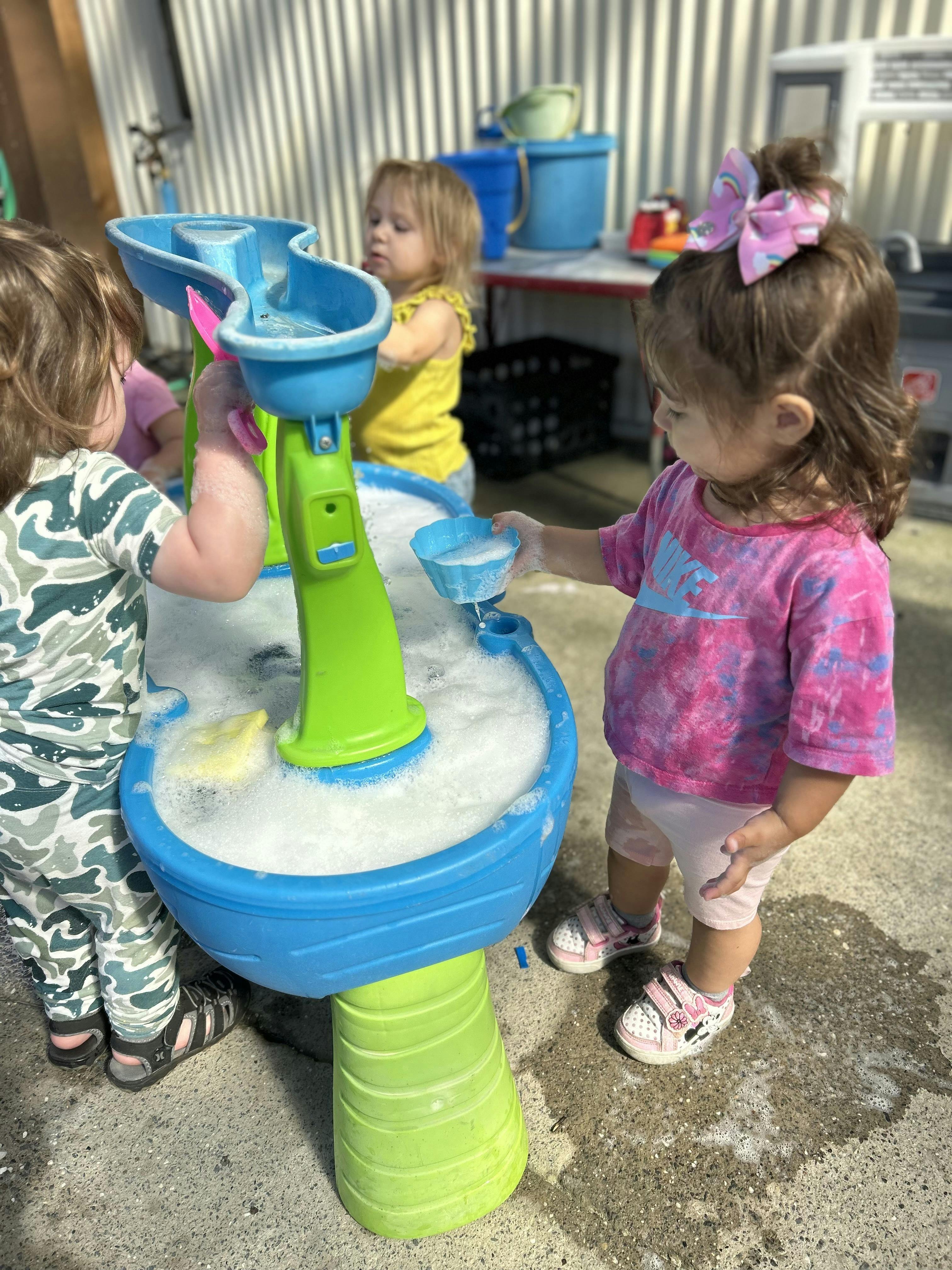 Children playing with a water table full of bubbles outdoors