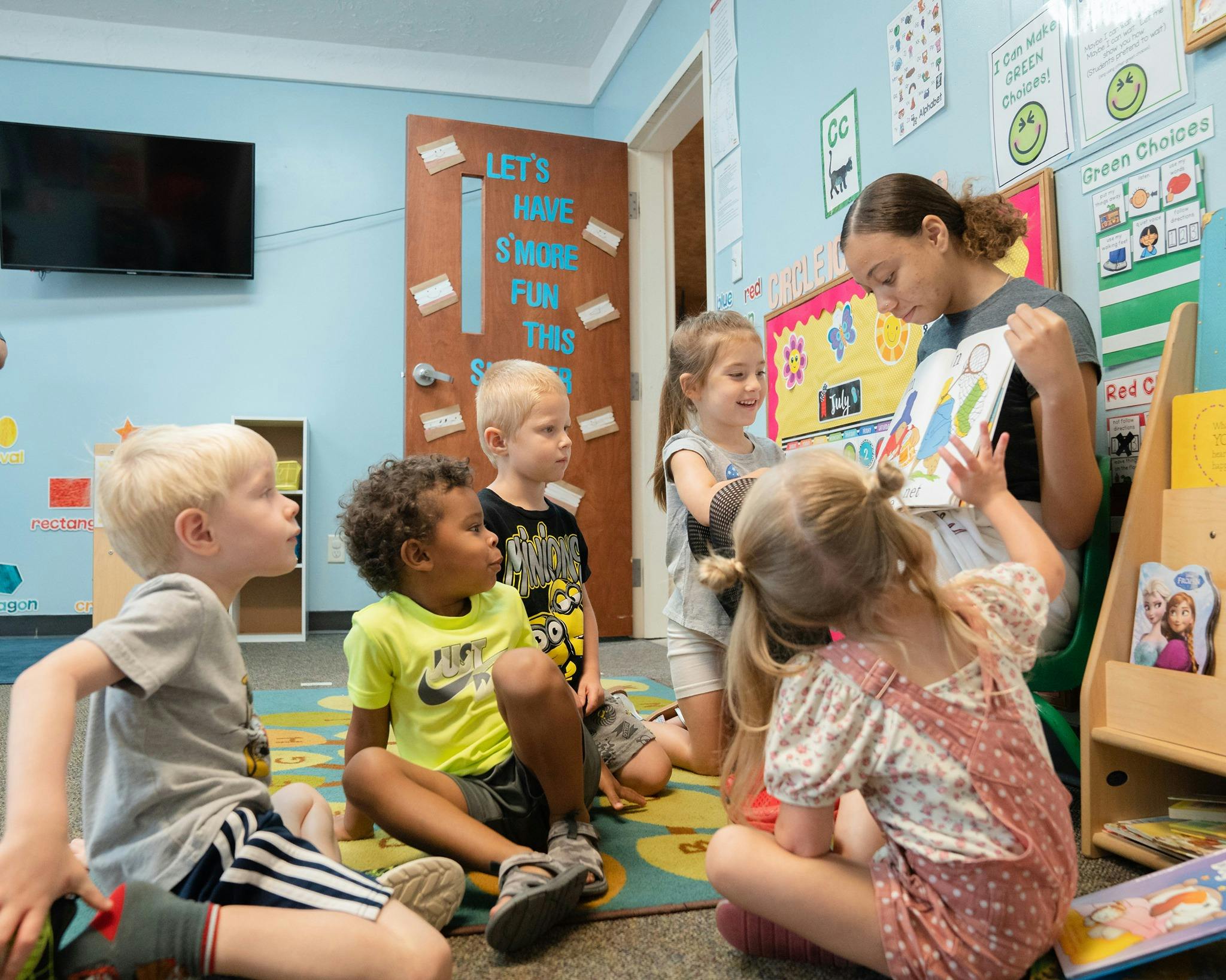 Person reading a book to a group of children in a classroom