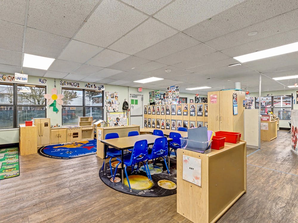 Classroom with tables, blue chairs, storage units, and windows