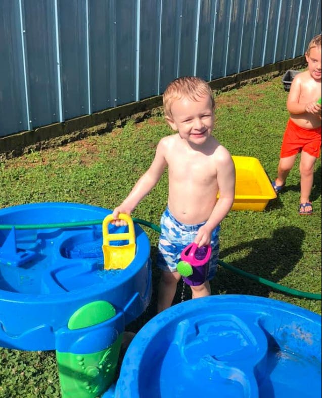 Child playing with water toys in a backyard