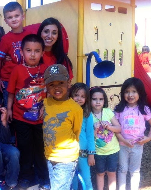 Adult and multiple children posing together on a playground