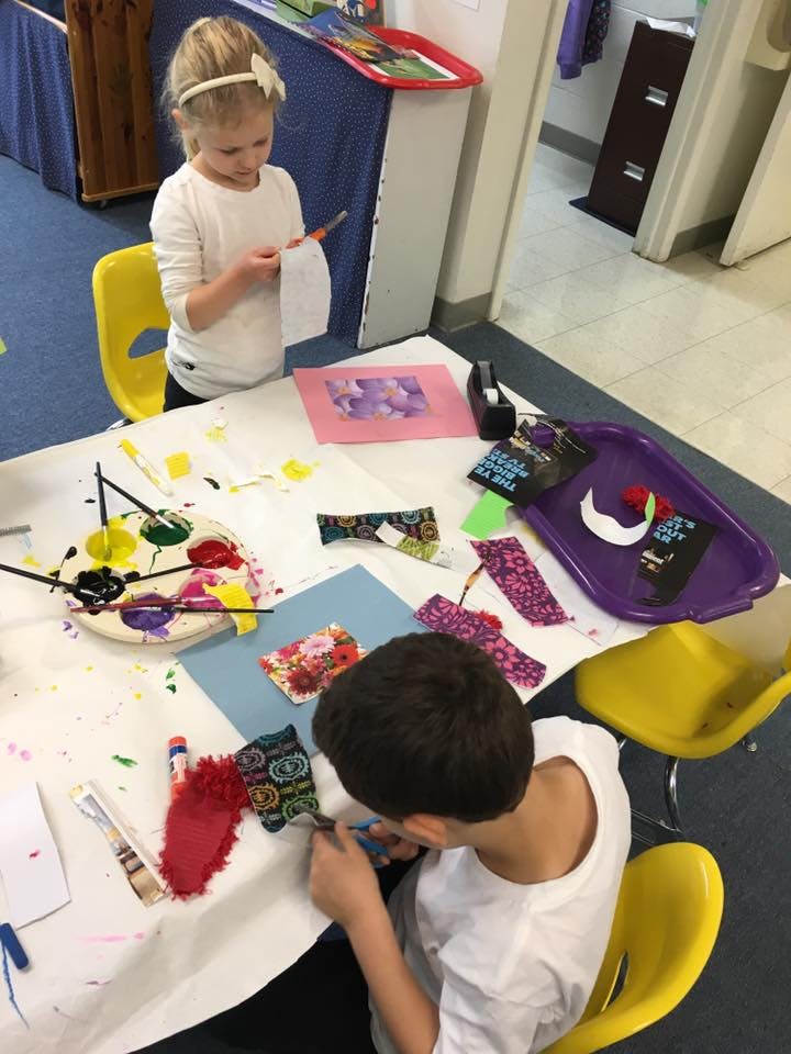 Two children doing crafts at a table with paint and fabric scraps