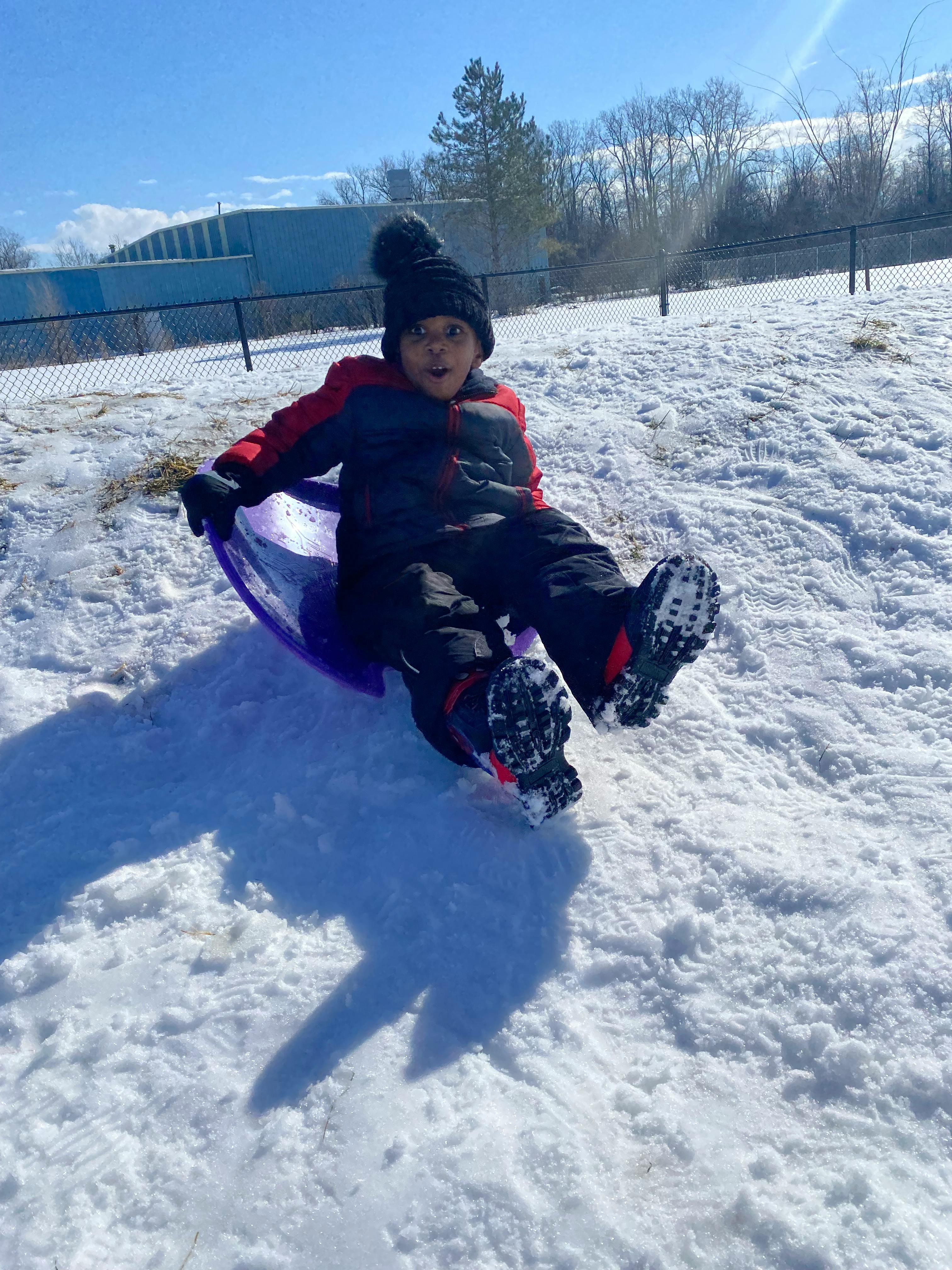 Child sledding down a snowy hill