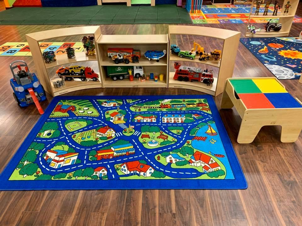 Playroom with a road map rug, toy shelves, and a small table