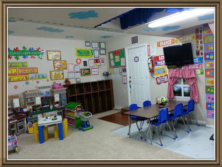 Classroom with play kitchen, cubbies, and small table with blue chairs