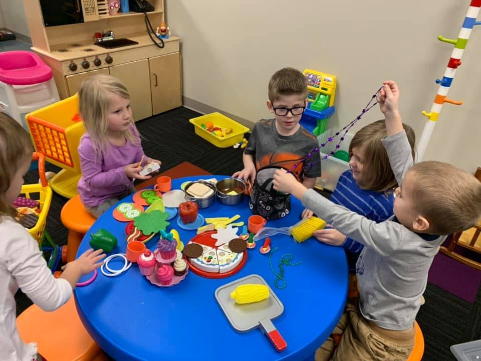 Children playing with toys at a blue table