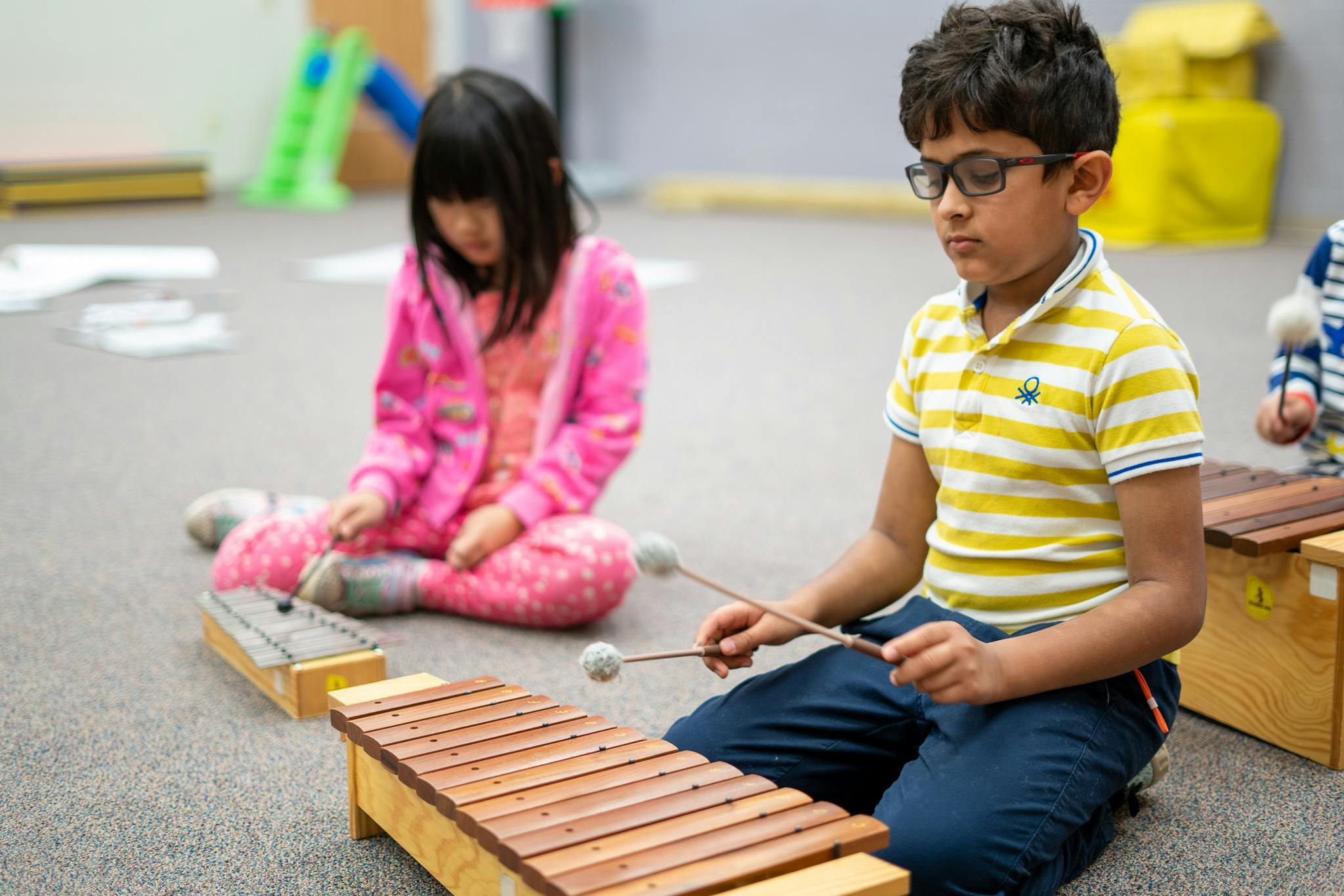 Two children playing xylophones on the floor