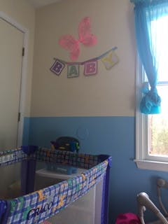 Crib in a room with a wall decoration that says BABY