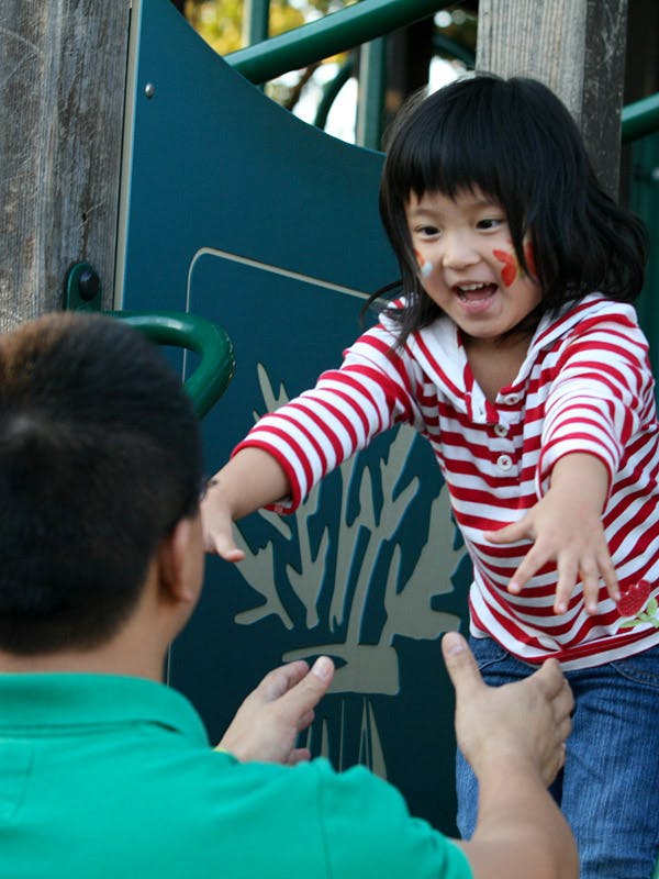 Child with face paint reaching out to a person
