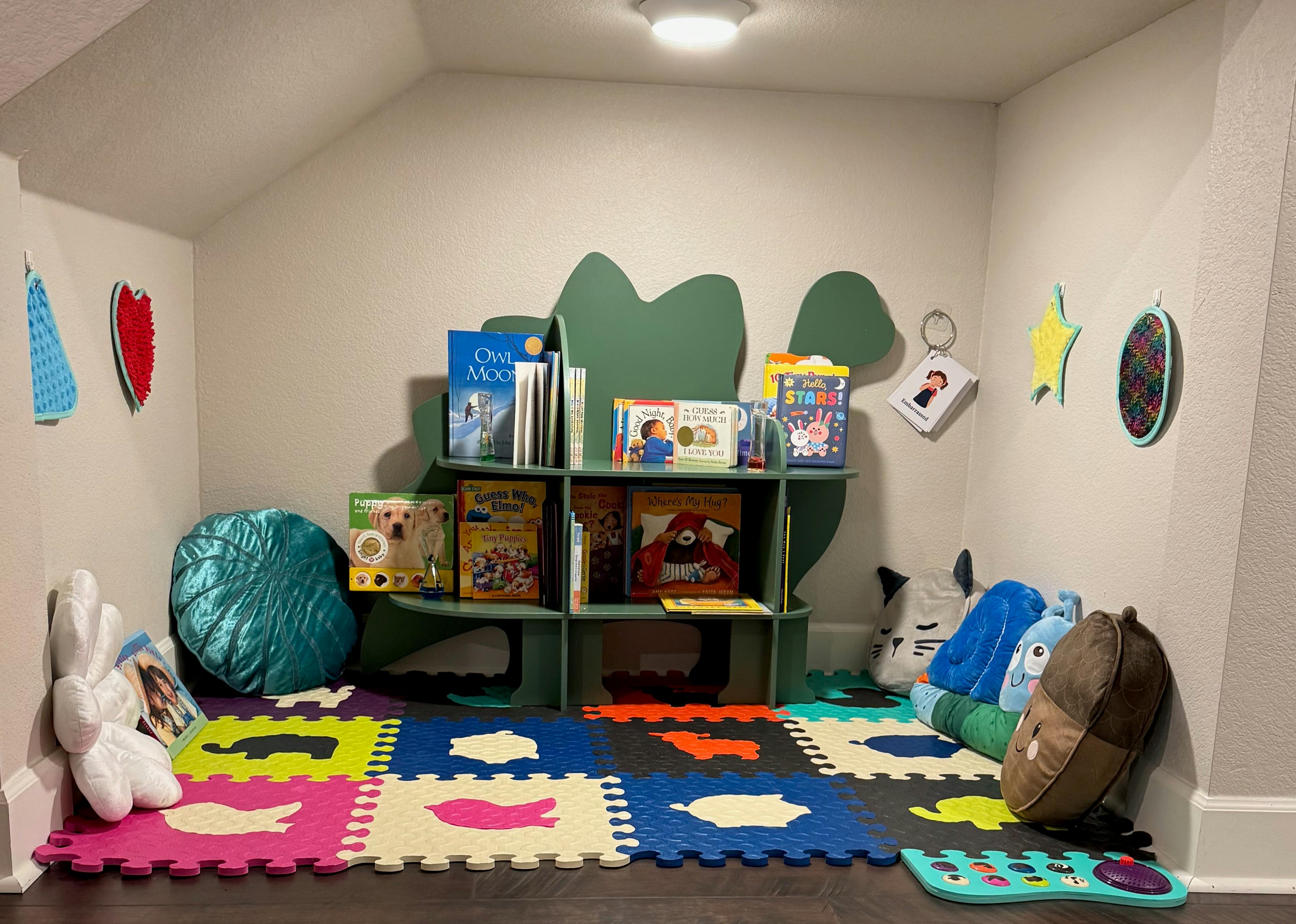 Children's play area with colorful floor mats and bookshelves filled with books