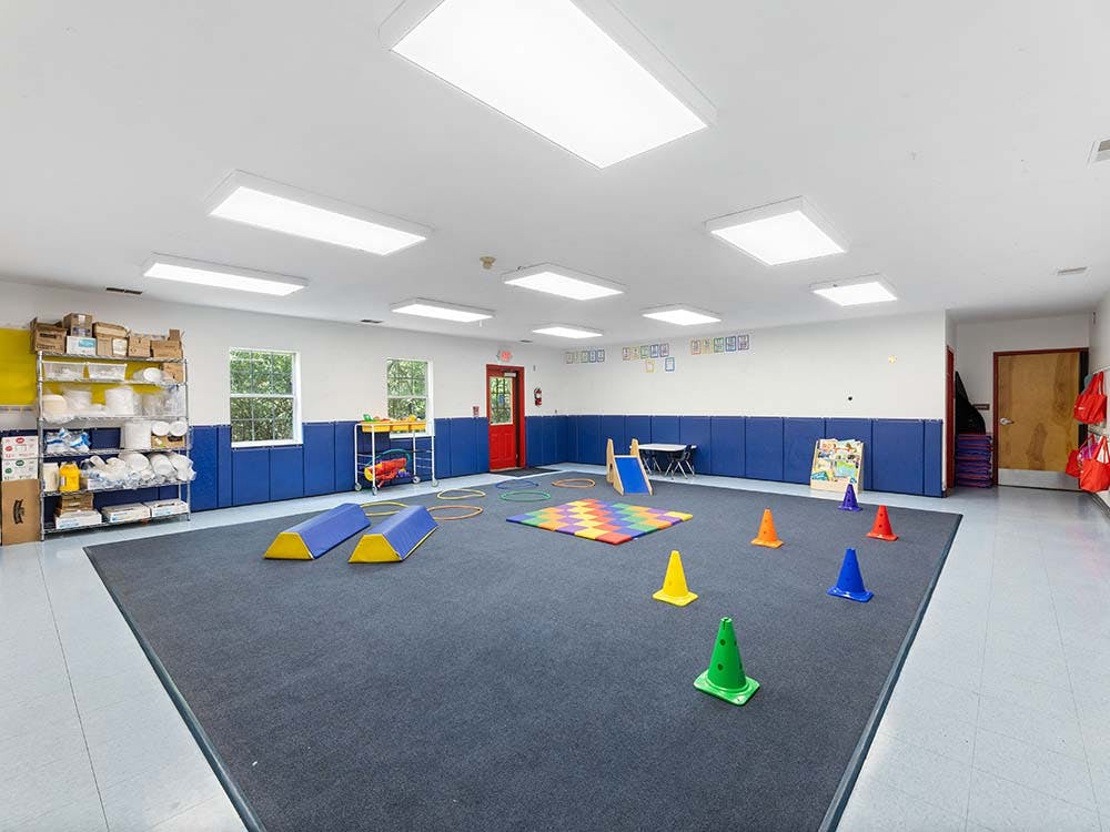 Classroom with blue padded walls, a dark gray rug, and colorful play equipment
