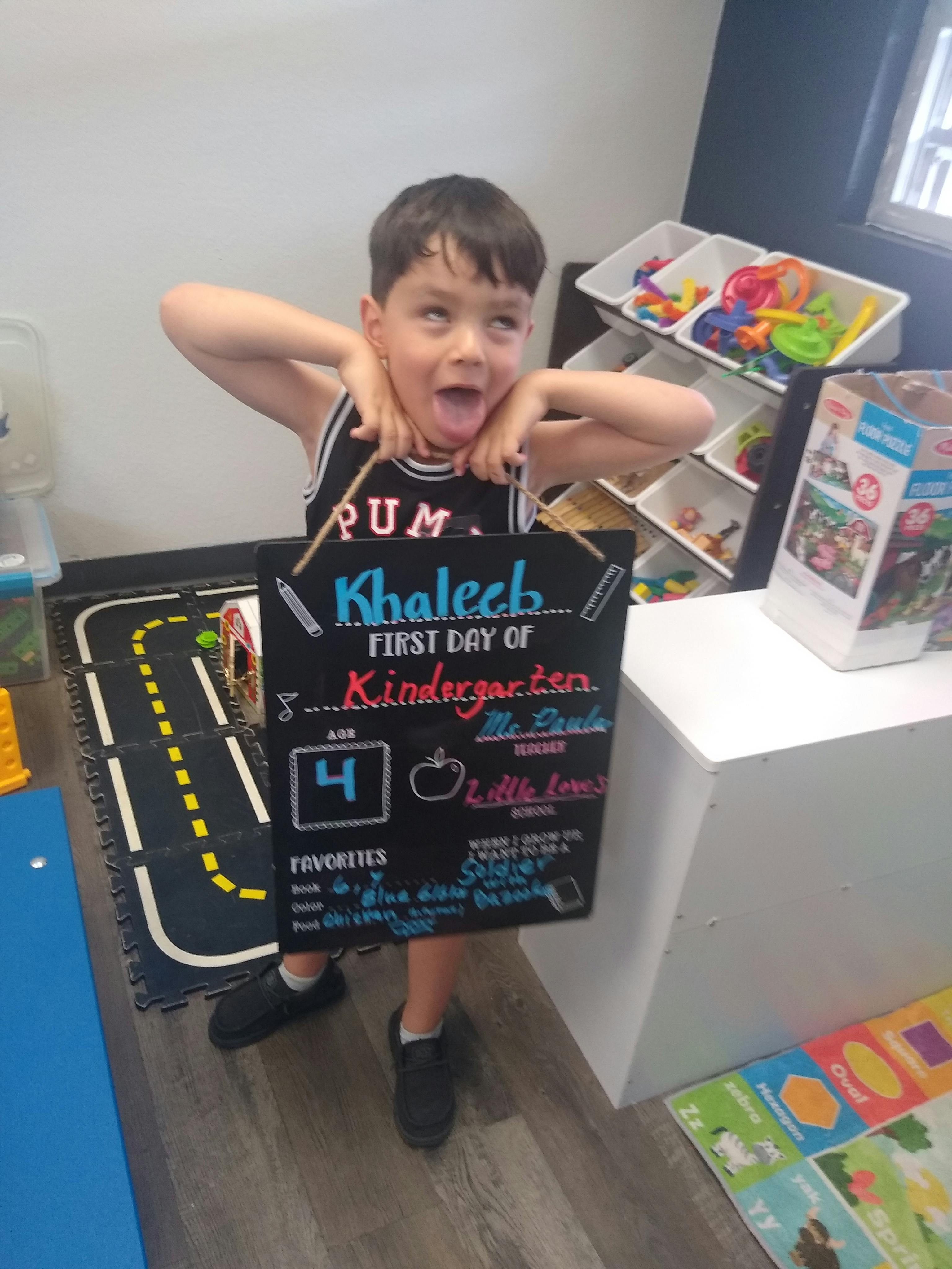 Child holding a first day of kindergarten sign