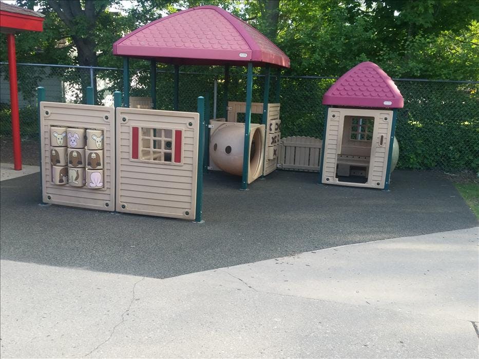 A beige children's playground structure with red roofs and a small tunnel