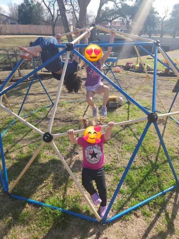Three children playing on a geometric dome climber