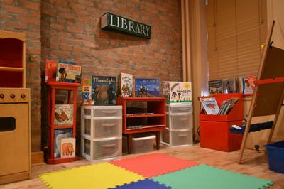 Children's play area with books, shelves, and a "LIBRARY" sign