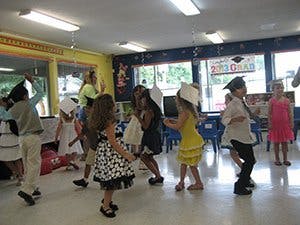 Children in graduation caps dancing in a classroom