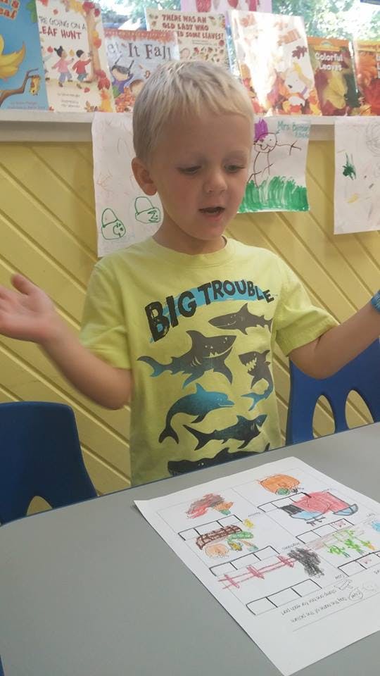 Child in a classroom looking at a drawing on a table