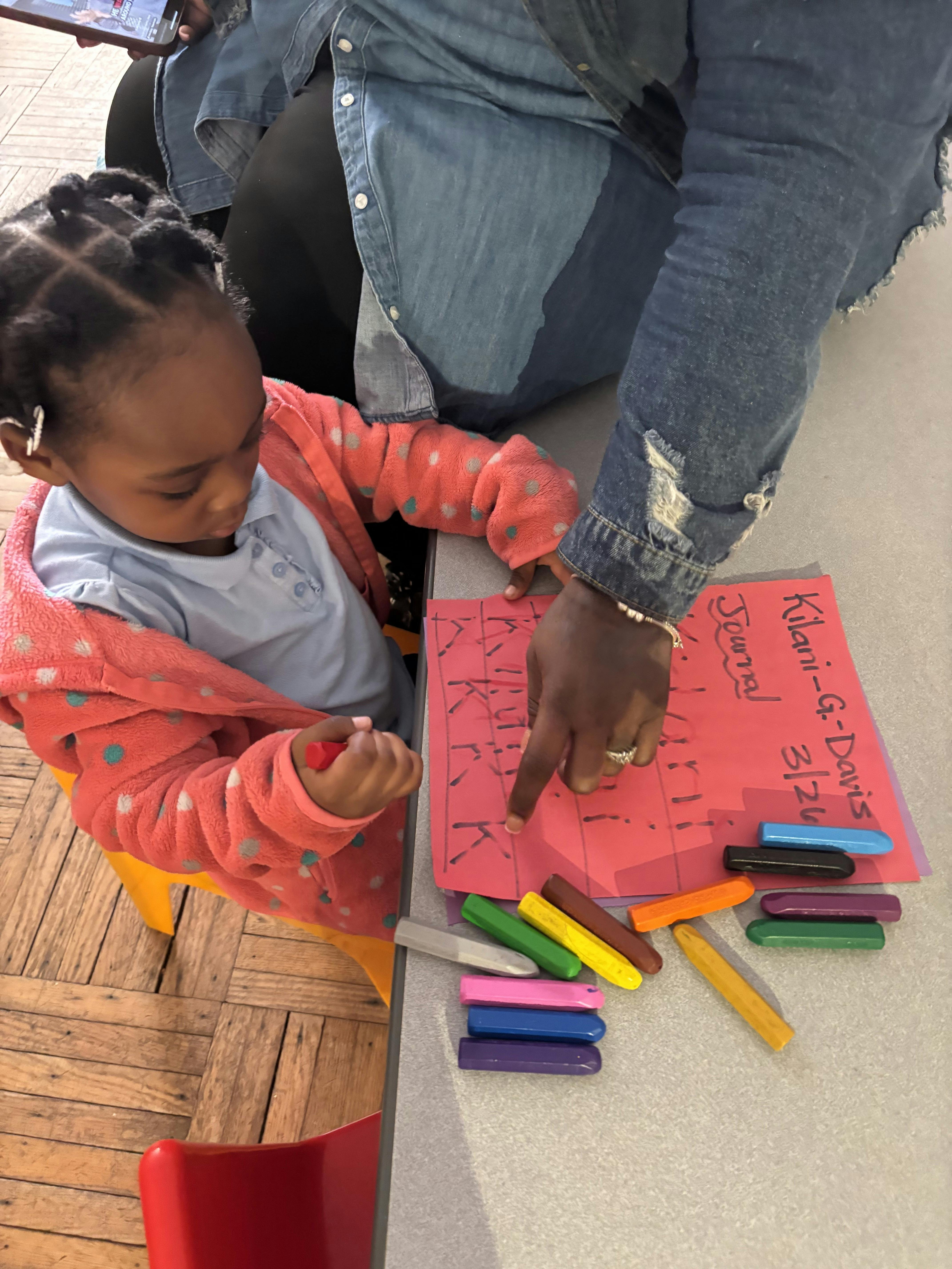 Child learning to write letters with an adult's hand guiding