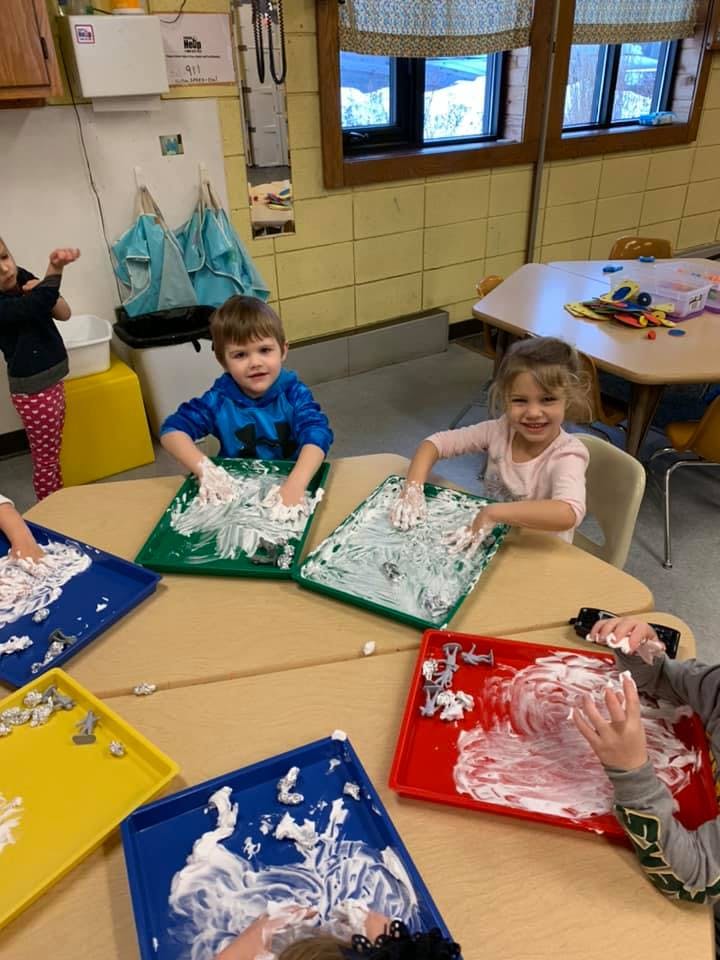 Children playing with shaving cream on trays