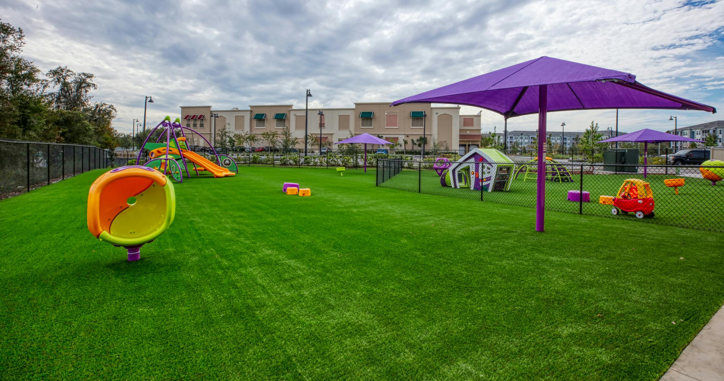 Outdoor playground with artificial turf, slides, and purple umbrellas