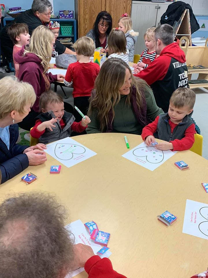 Adults and children sitting around a table doing crafts