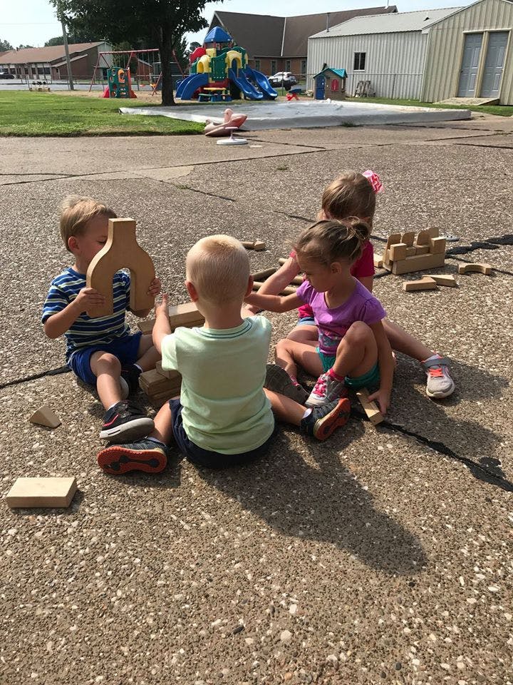 Children playing with wooden blocks outdoors