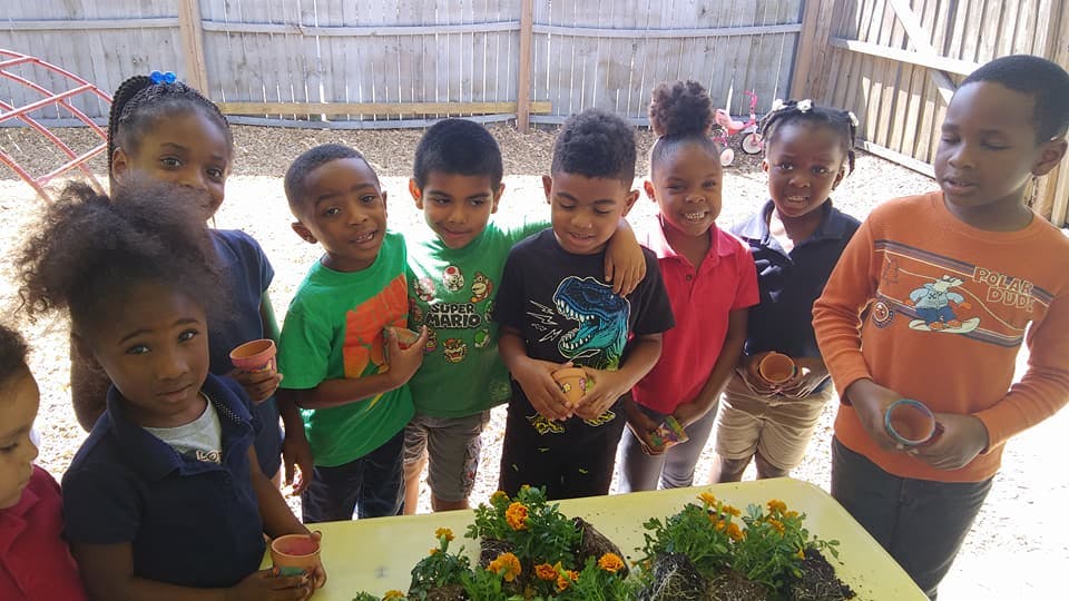 Group of children gathered around a table with small plants