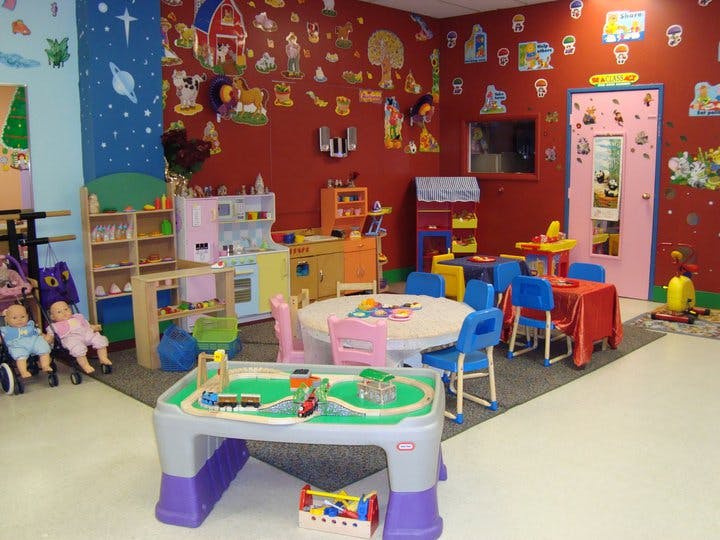 Playroom with small tables and chairs, toy kitchen, and train set